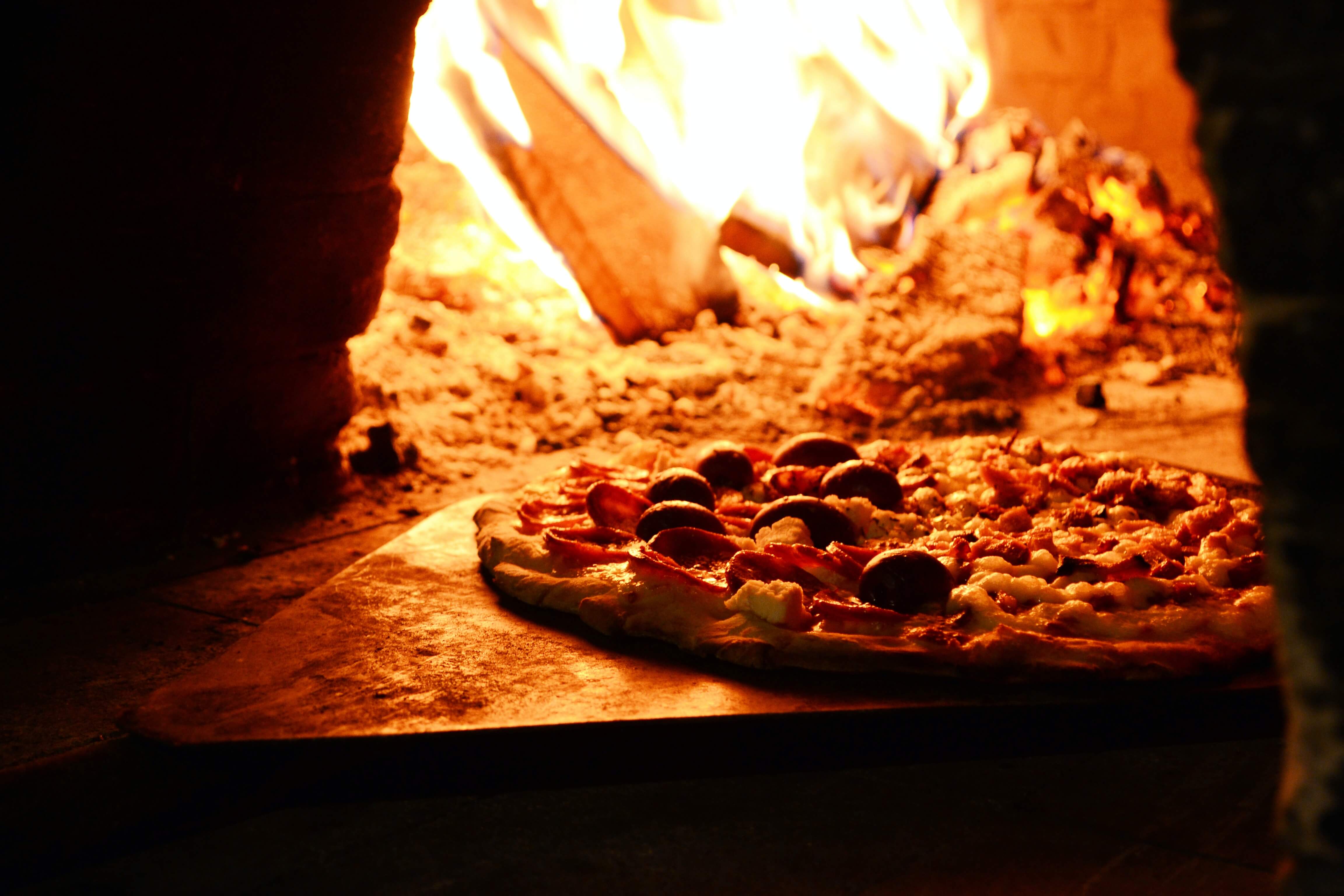Pizza im Steinofen mit Holzfeuer